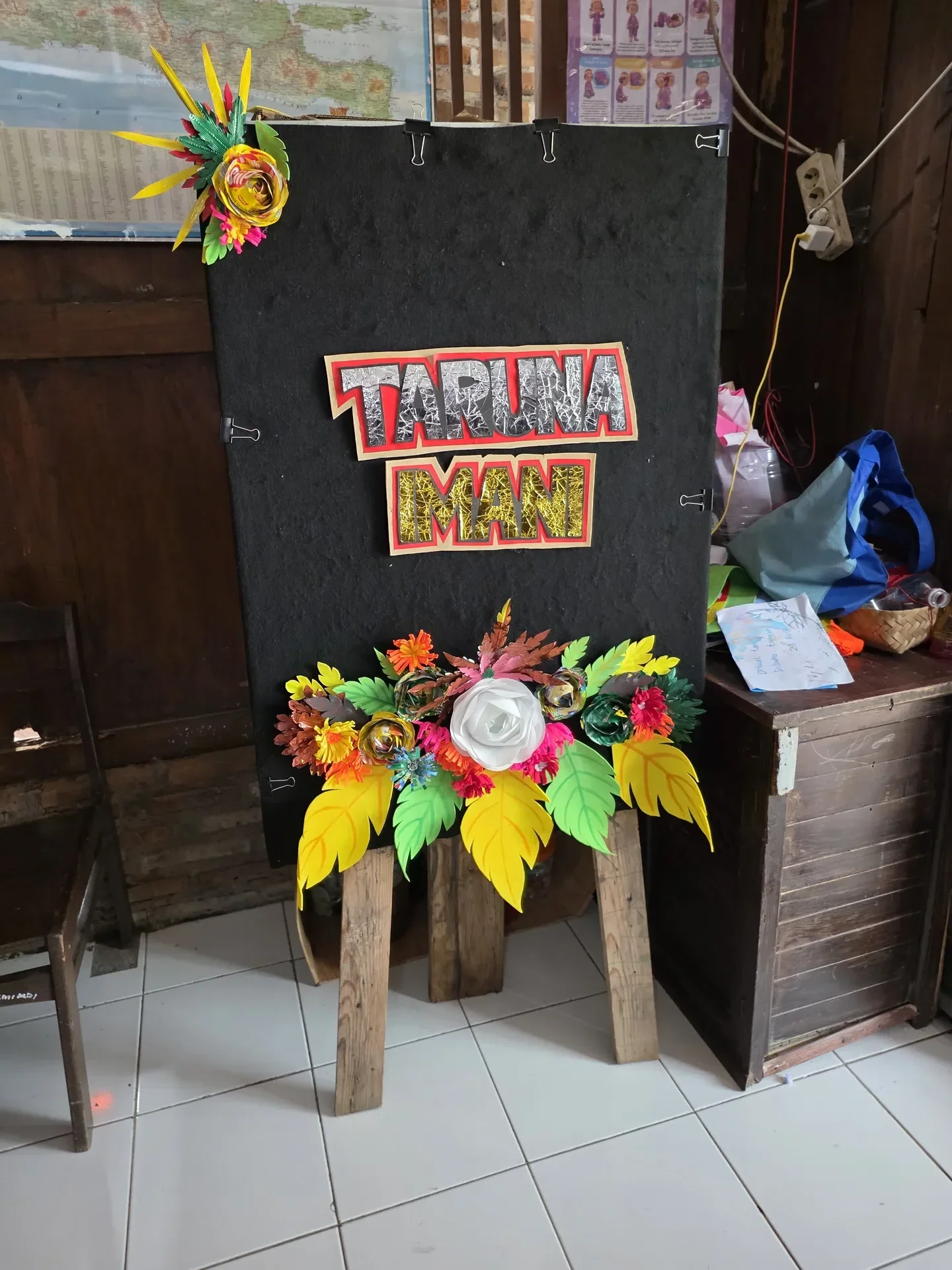 Papan nama Sekolah Inklusi Taruna Imani dengan hiasan bunga warna-warni karya siswa ABK